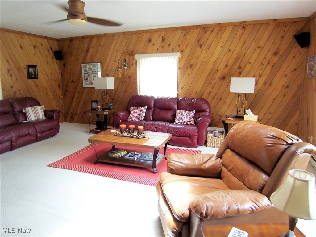 Living room featuring carpet, wood walls, and ceiling fan