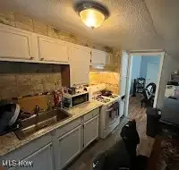 Kitchen with gray cabinets, light countertops, and stove