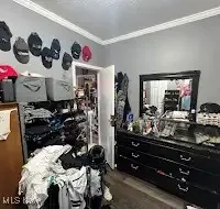 Bedroom with crown molding and wood finished floors