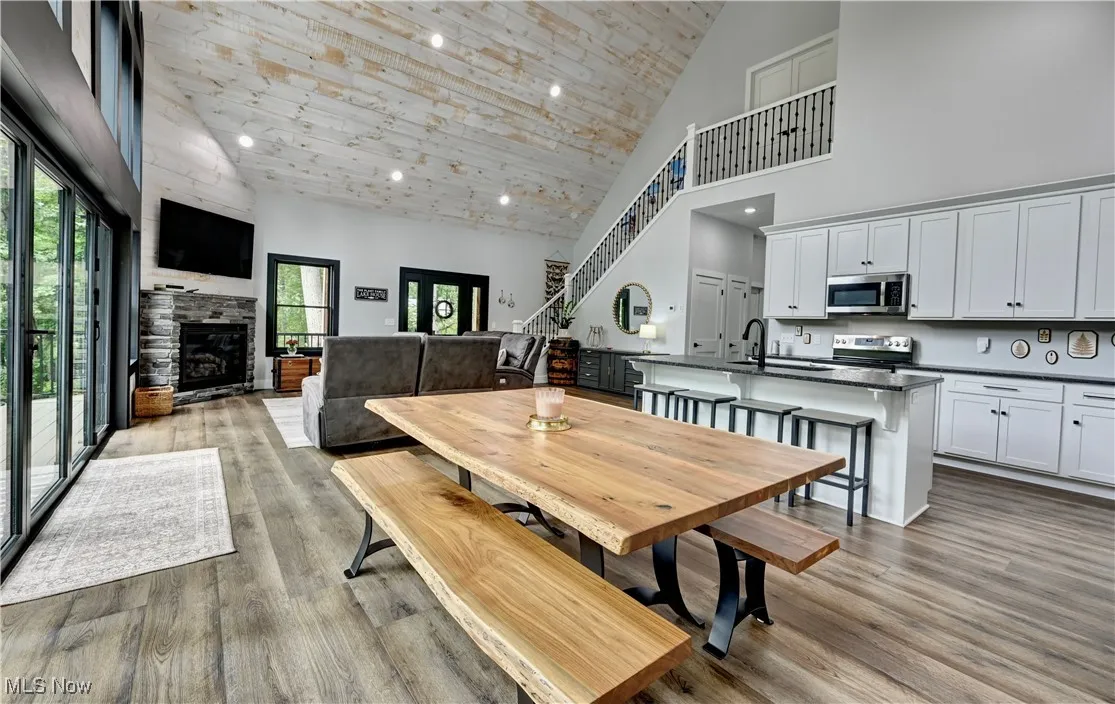 Dining space featuring high vaulted ceiling, wooden ceiling, wood finished floors, a fireplace, and recessed lighting