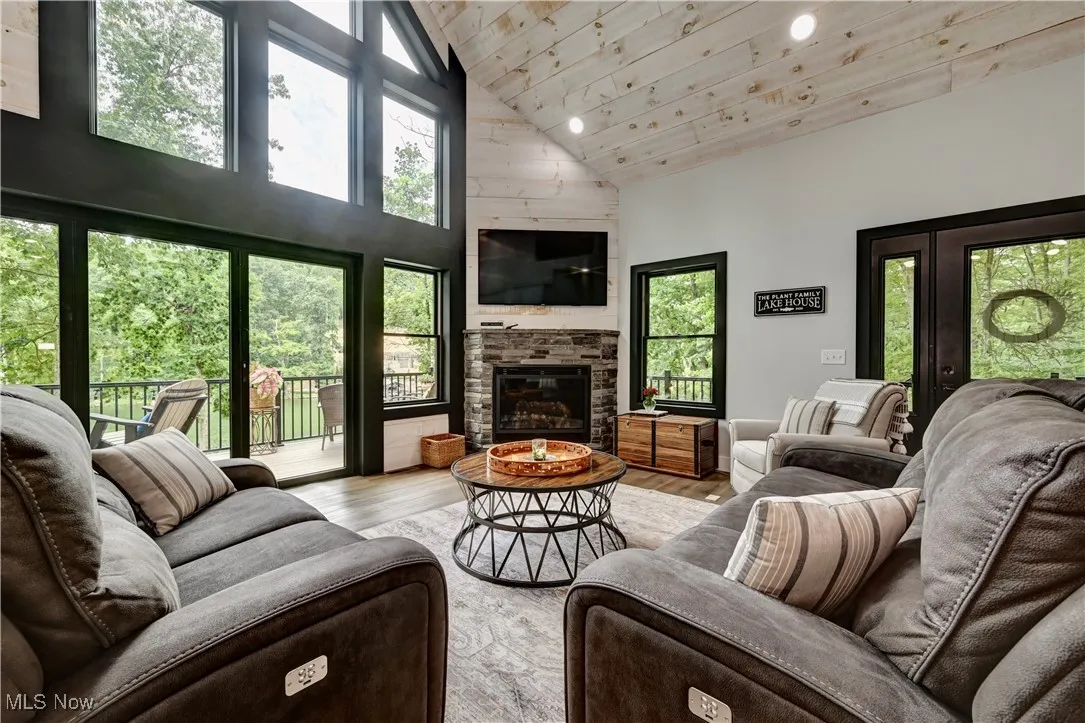 Living room featuring high vaulted ceiling, wooden ceiling, wood finished floors, a fireplace, and recessed lighting