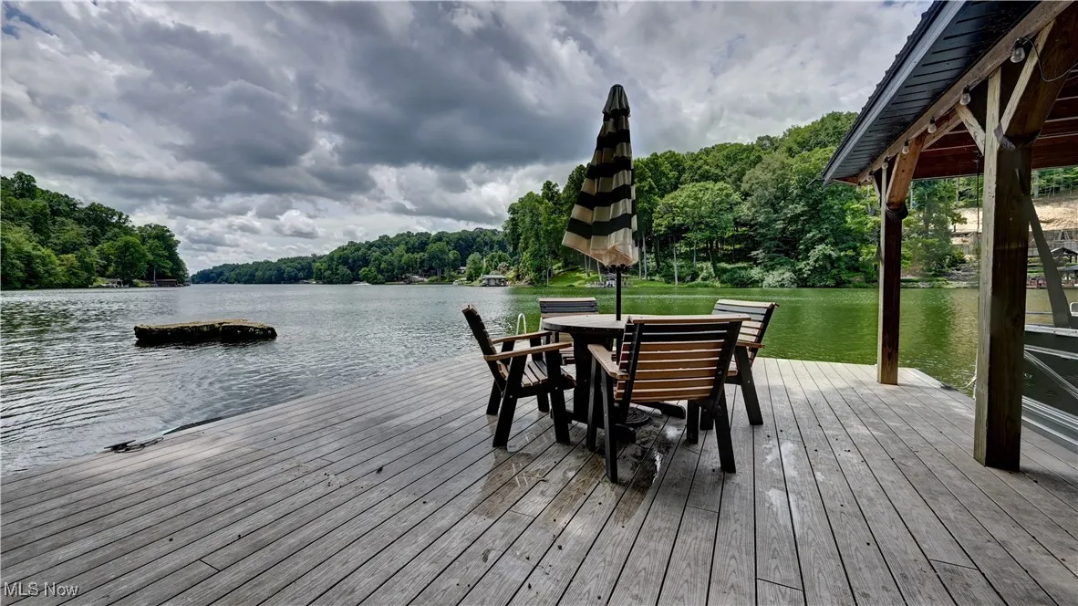 Dock featuring a water view, a forest view, and outdoor dining space