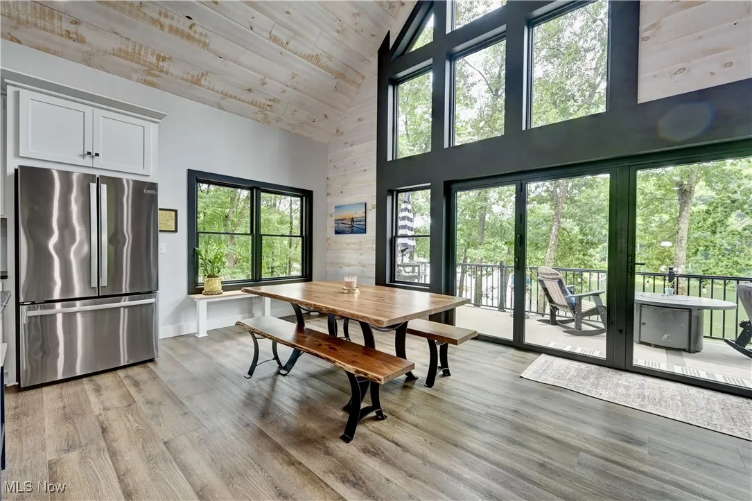 Dining room featuring high vaulted ceiling, plenty of natural light, light wood-type flooring, and wood ceiling