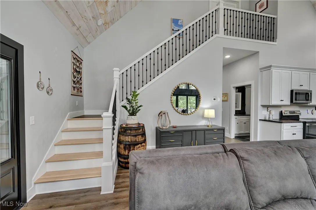 Staircase with high vaulted ceiling, wood finished floors, and recessed lighting