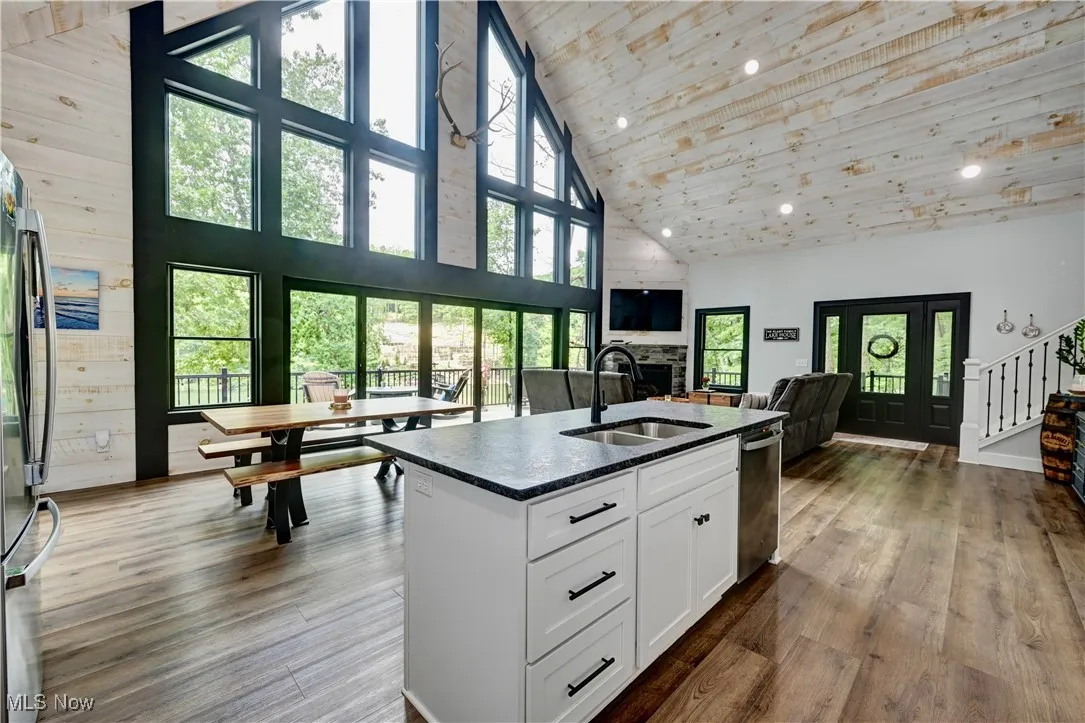 Kitchen with high vaulted ceiling, wood ceiling, white cabinetry, appliances with stainless steel finishes, and dark stone counters
