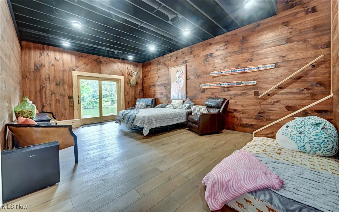 Basement living room area featuring access to exterior, wood walls, and wood-type flooring