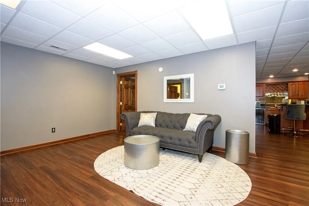 Sitting area featuring dark wood-type flooring, beverage cooler, a drop ceiling, and recessed lighting