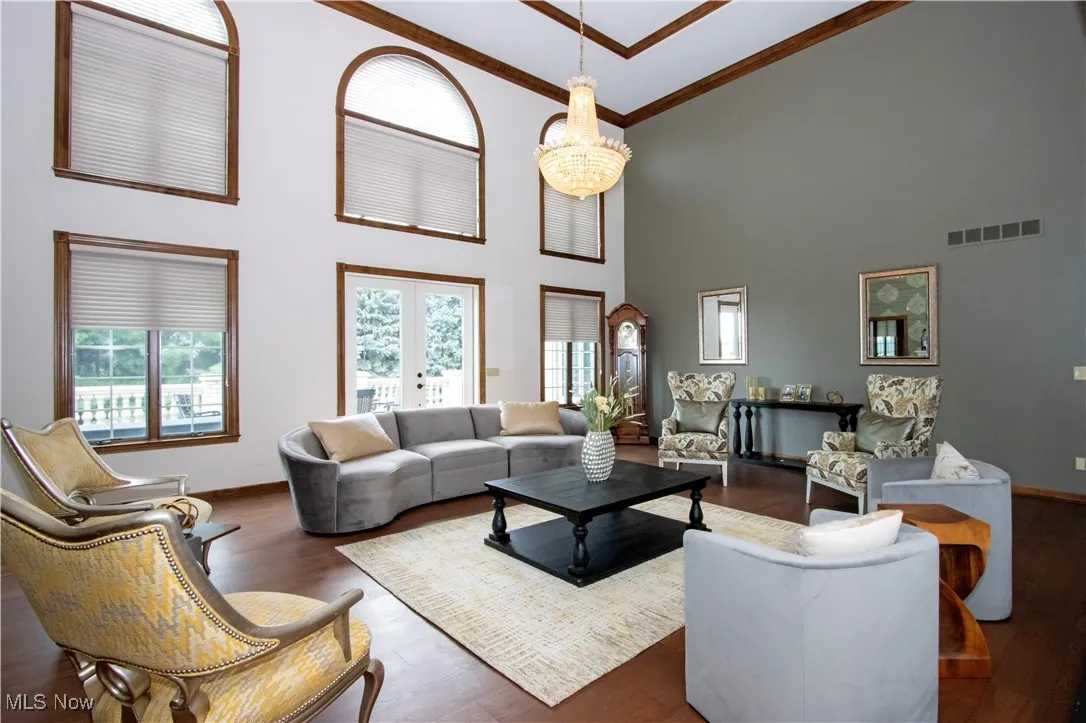 Living room with plenty of natural light, high vaulted ceiling, wood finished floors, french doors, and ornamental molding