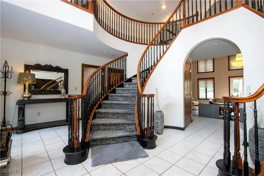 Stairway featuring arched walkways, a towering ceiling, and tile patterned flooring