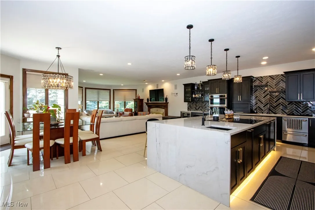 Kitchen with a chandelier, decorative backsplash, recessed lighting, pendant lighting, and an island with sink