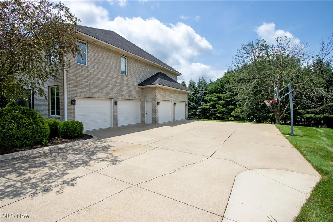 View of side of property 4 car garage and driveway, brick siding, and a garage