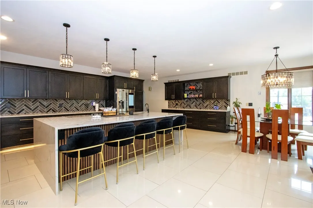 Kitchen with tasteful backsplash, a chandelier, a breakfast bar, stainless steel fridge, and a large island
