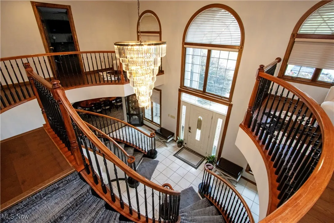 Tiled foyer entrance featuring a chandelier, stairs, and a high ceiling