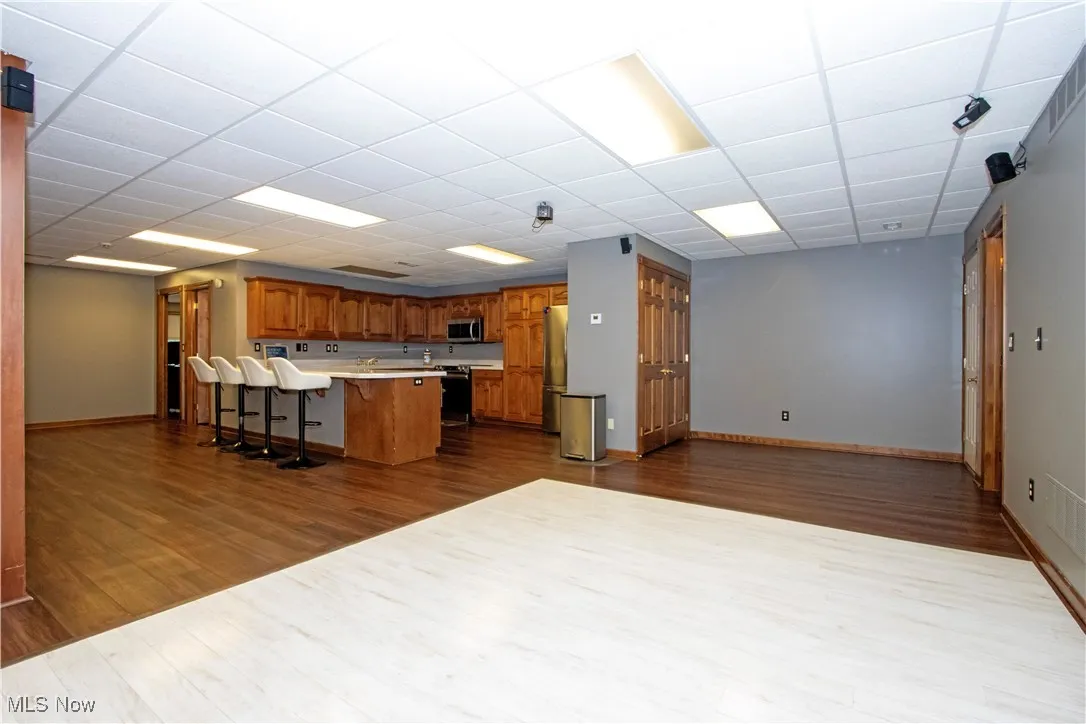 Kitchen  in lower level featuring dark wood-style floors, brown cabinets, a kitchen breakfast bar, a peninsula, and light countertops and dance floor