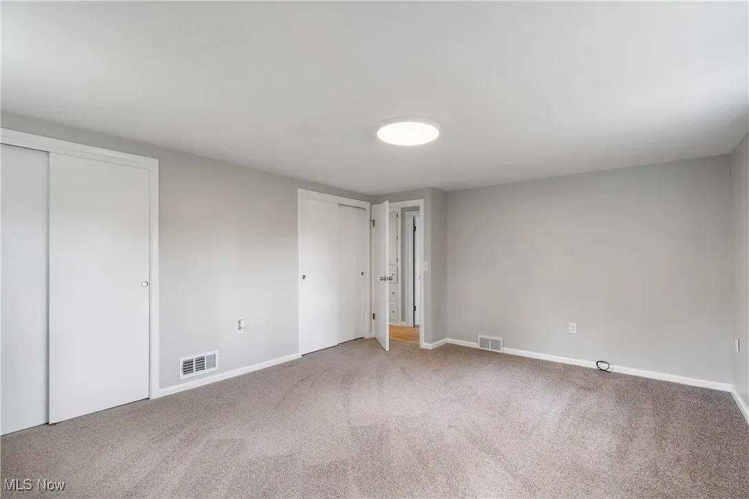 Unfurnished bedroom with two closets and carpet floors