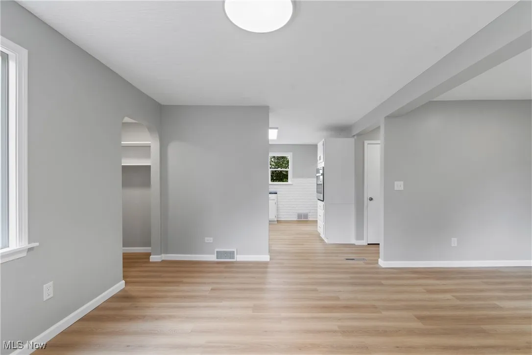 Dining area with arched walkways and light wood-style floors