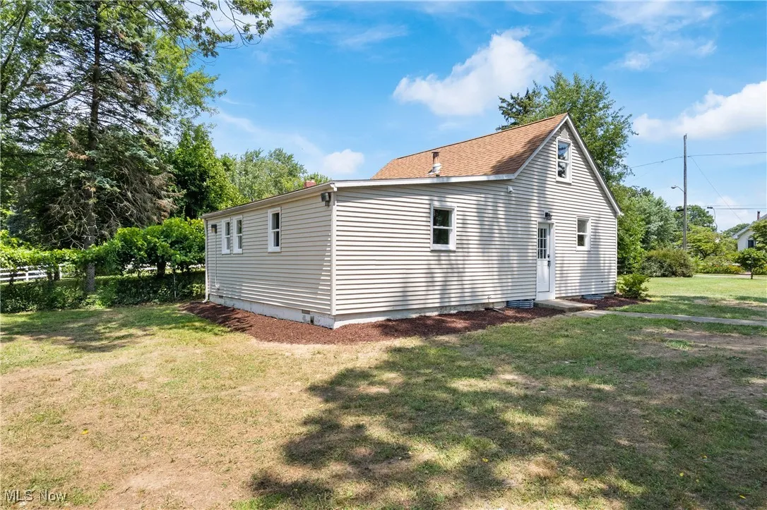 View of side of property featuring a lawn and crawl space