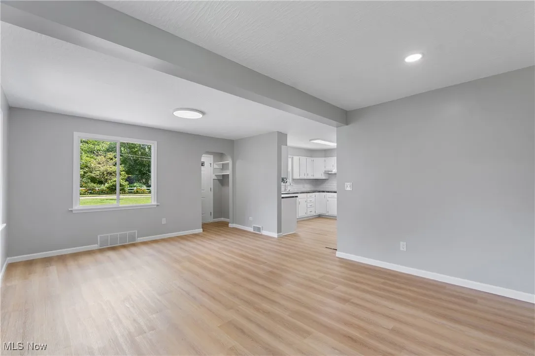 Unfurnished living room with arched walkways and light wood finished floors