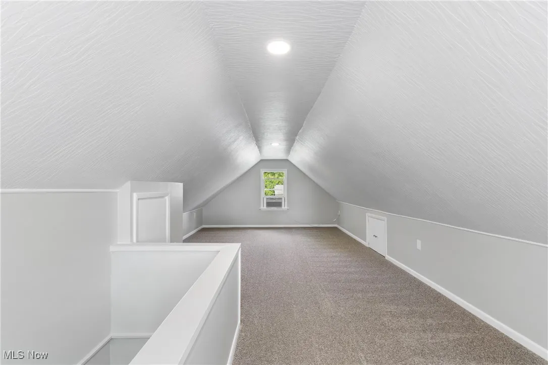 Additional living space with lofted ceiling and carpet flooring