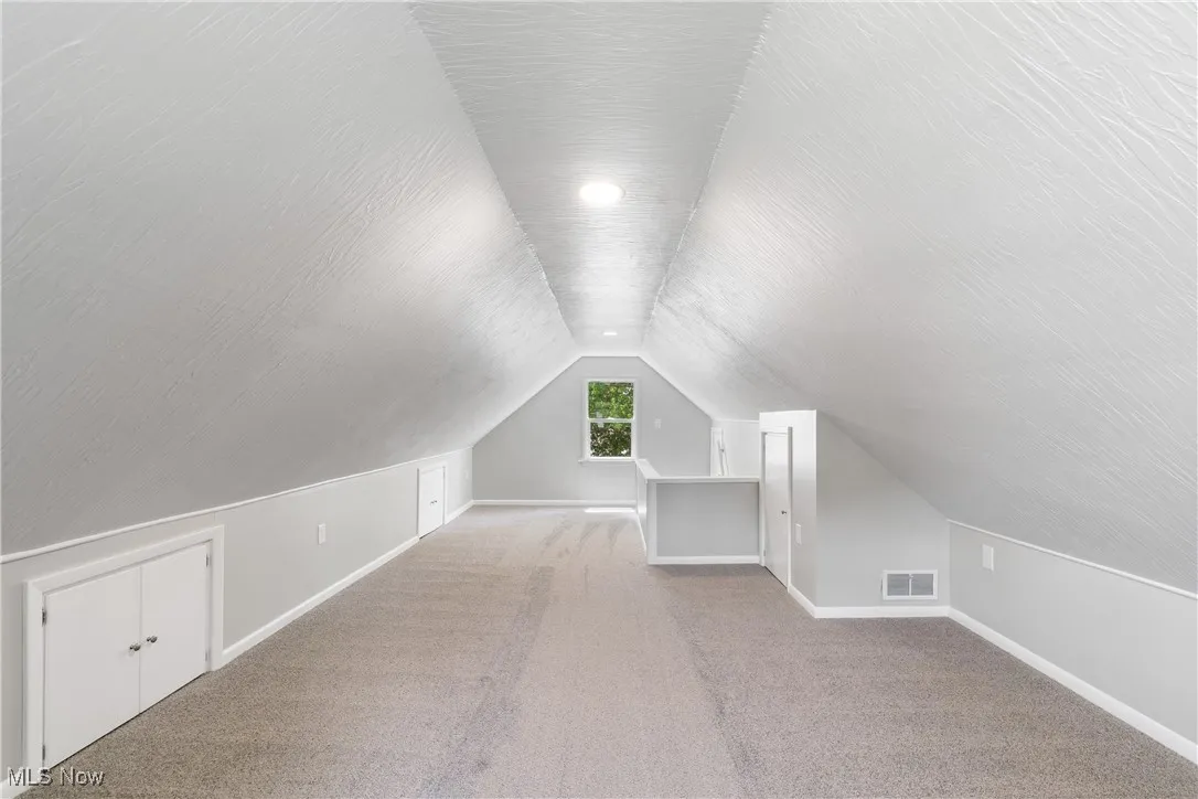 Additional living space featuring vaulted ceiling and carpet flooring