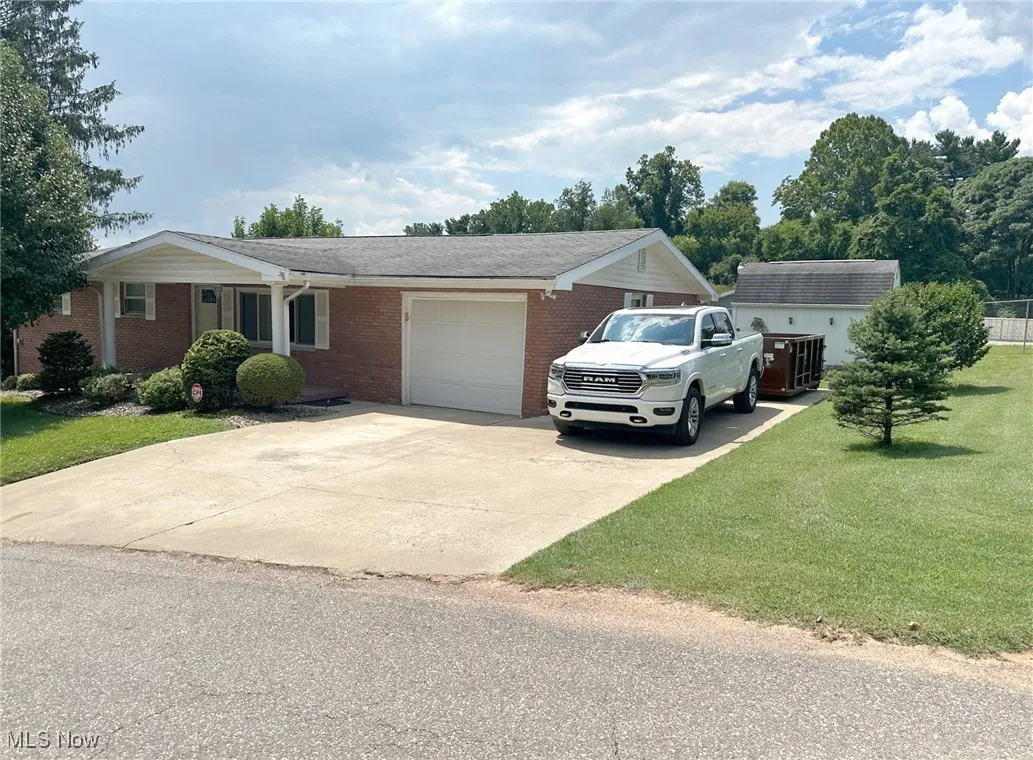 Single story home with an attached garage, concrete driveway, a front lawn, and brick siding