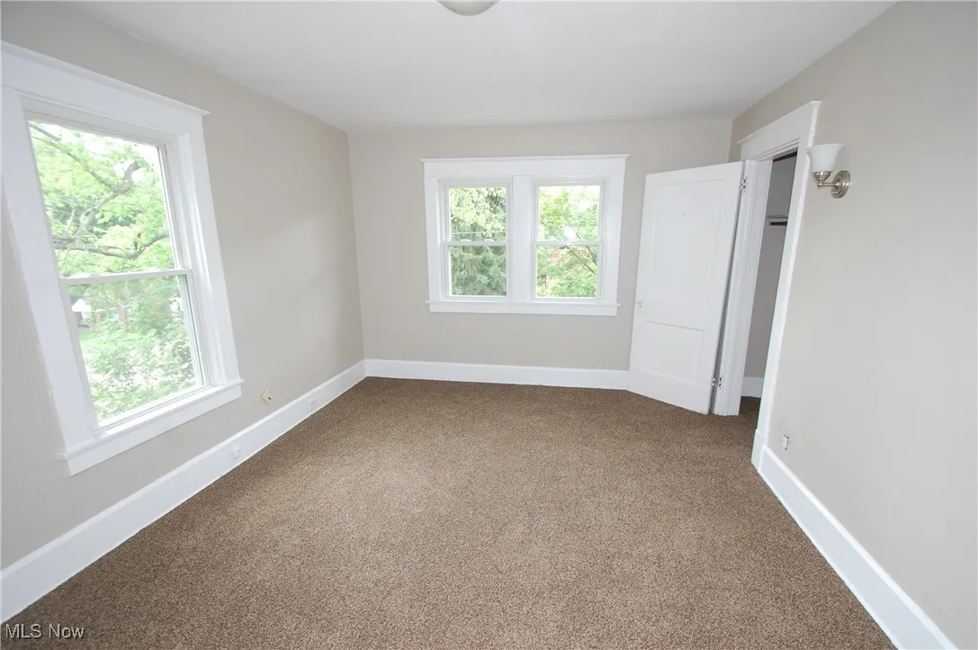 Empty room with plenty of natural light and dark colored carpet