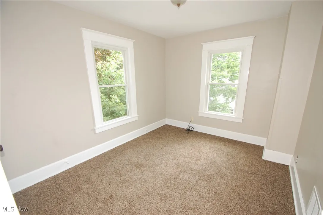 Unfurnished room featuring healthy amount of natural light and dark carpet