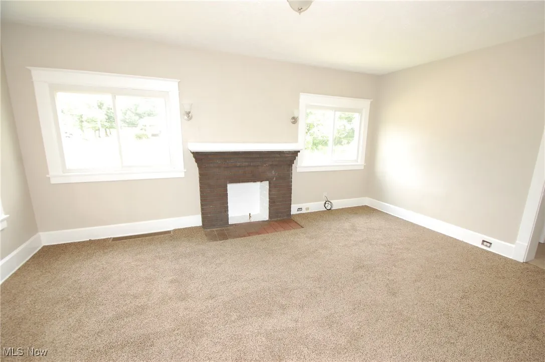 Unfurnished living room featuring a fireplace and carpet flooring