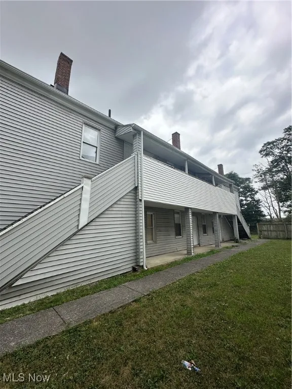 View of property exterior featuring a chimney and a yard