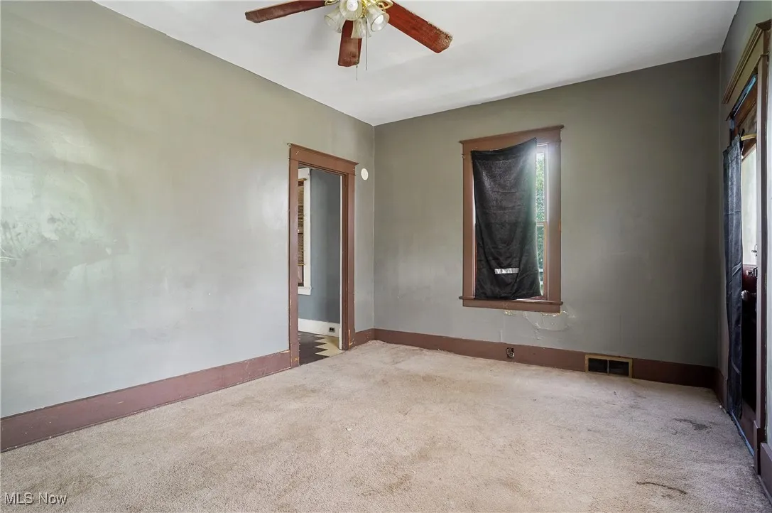 Carpeted spare room featuring a ceiling fan and healthy amount of natural light