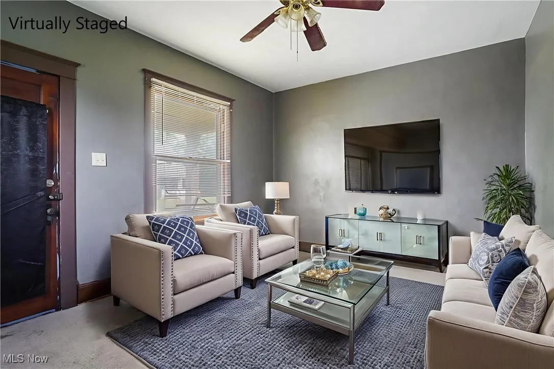 Carpeted living room with ceiling fan and baseboards