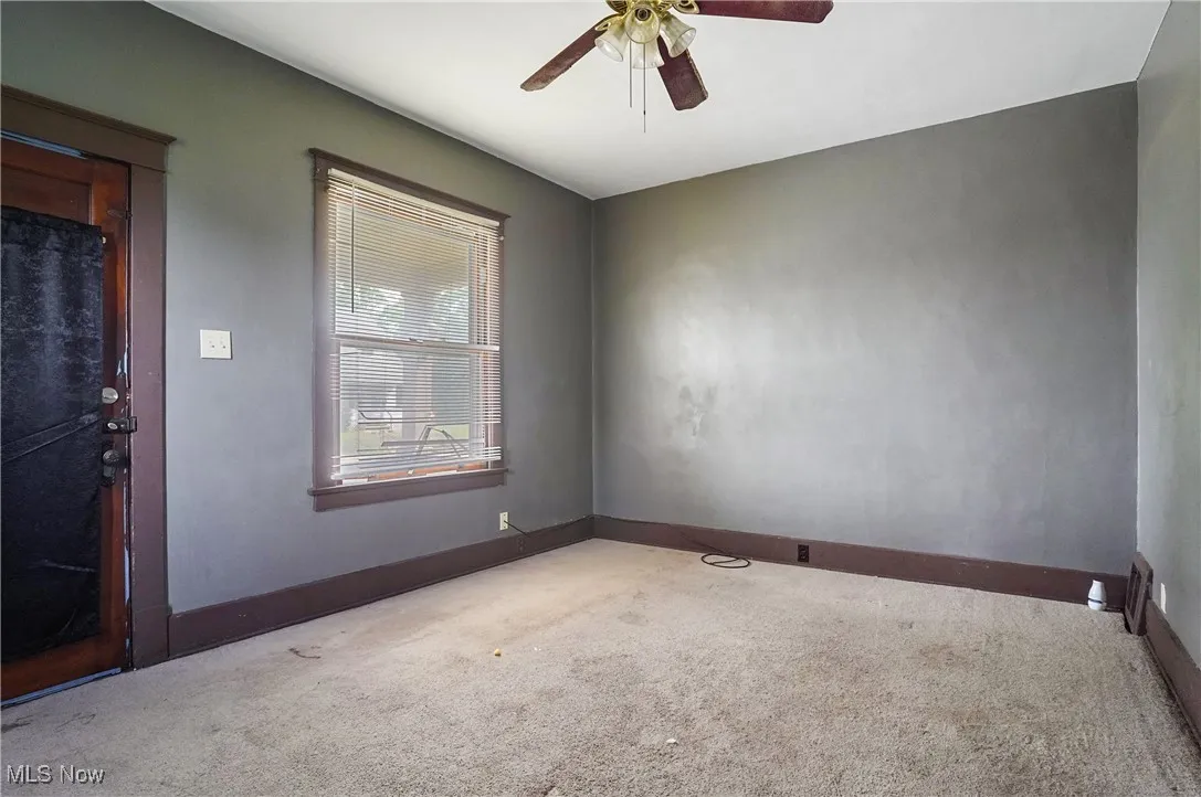 Carpeted spare room with ceiling fan and baseboards