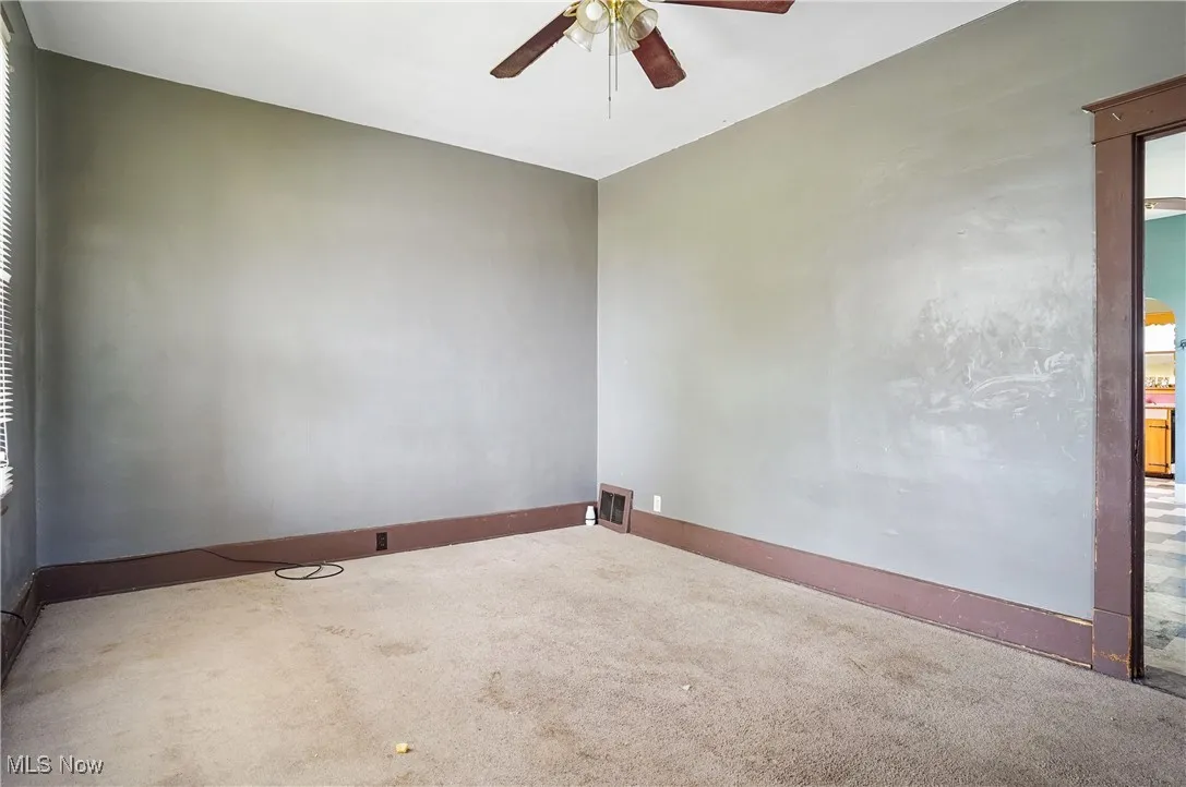 Carpeted empty room featuring ceiling fan and baseboards