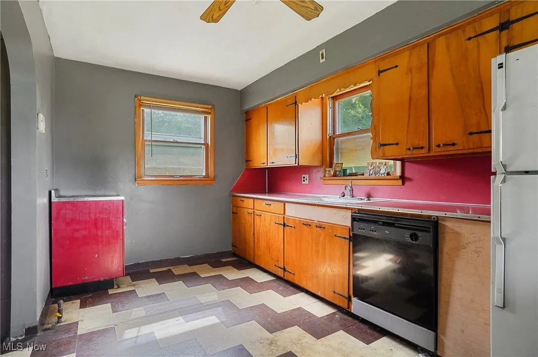 Kitchen featuring light floors, healthy amount of natural light, black dishwasher, and ceiling fan