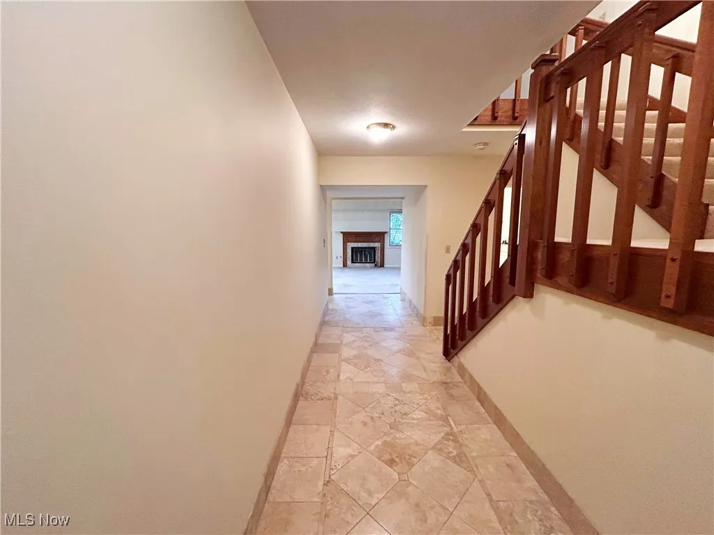 Foyer hallway featuring stairway to second floor, view of the living room, and stone tile floors