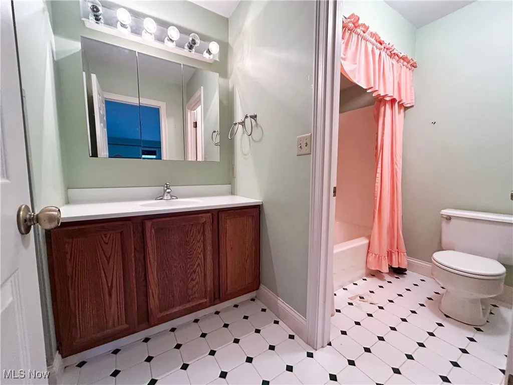 Master bathroom featuring vanity, toilet, tile patterned floors, and shower / tub combo with curtain