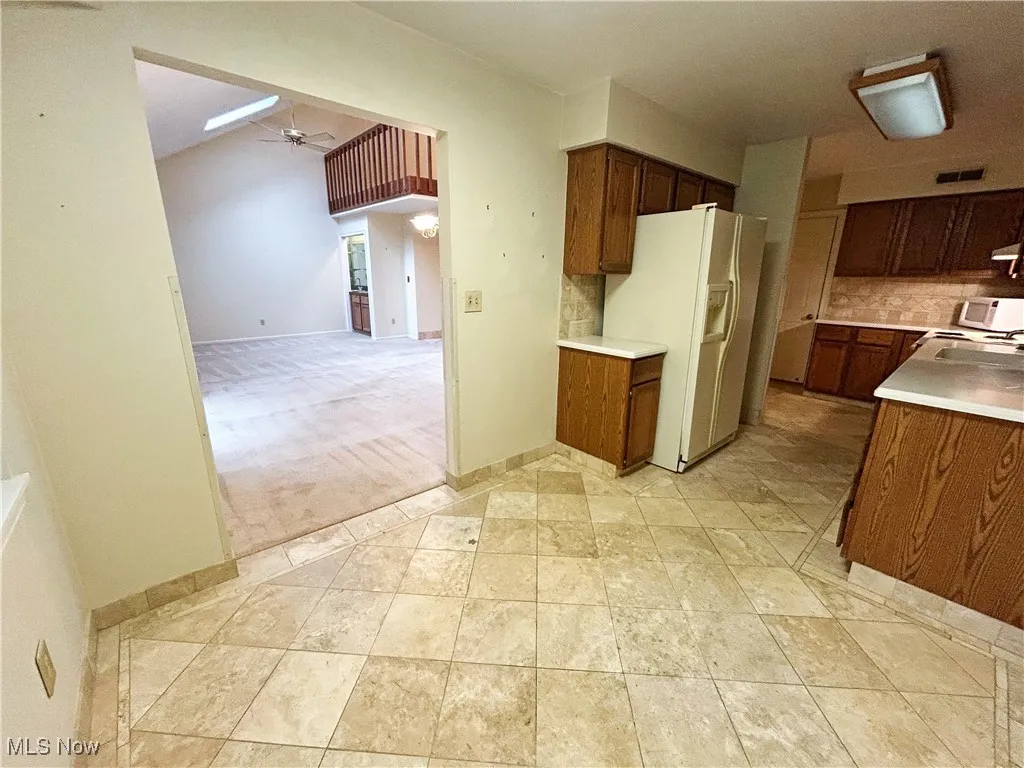 Kitchen featuring white appliances, decorative backsplash, and light countertops