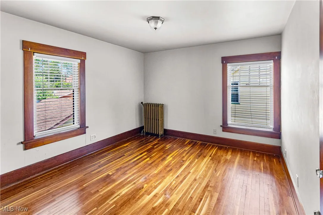 Unfurnished room with wood-type flooring and radiator heating unit