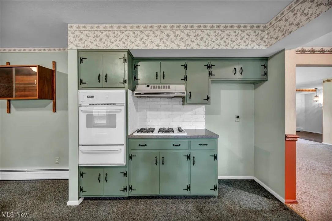 Kitchen featuring green cabinets, berber carpet and white oven