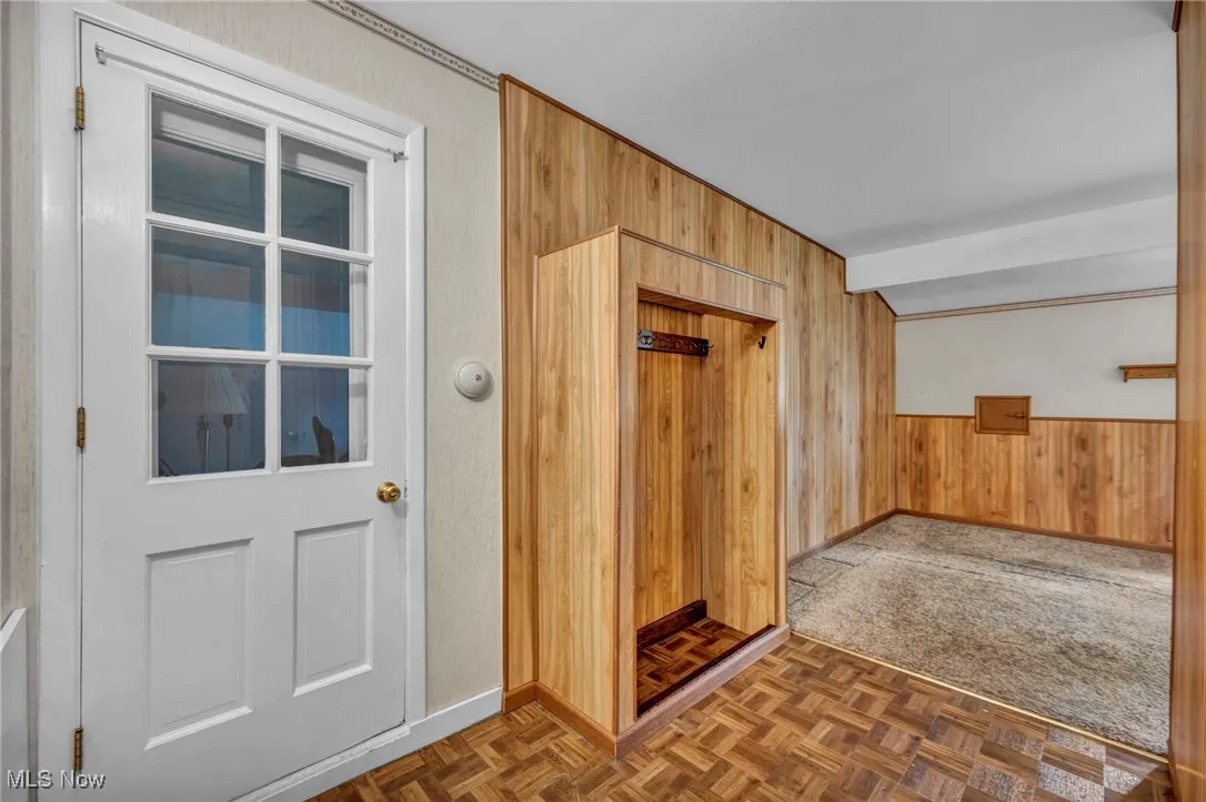 Foyer entrance featuring wooden walls and baseboards