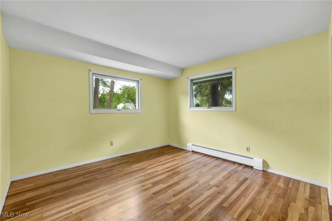 bedroom with real hardwood flooring and natural lighting