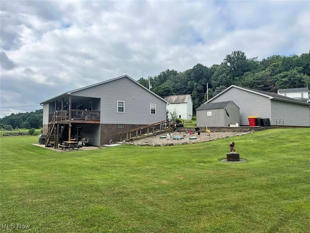 Rear view of property featuring a fire pit, a yard, a deck, and stairs