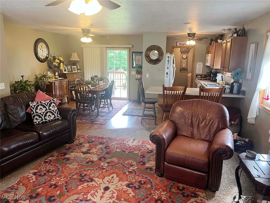 Living room featuring ceiling fan, wood finished floors, and a textured ceiling