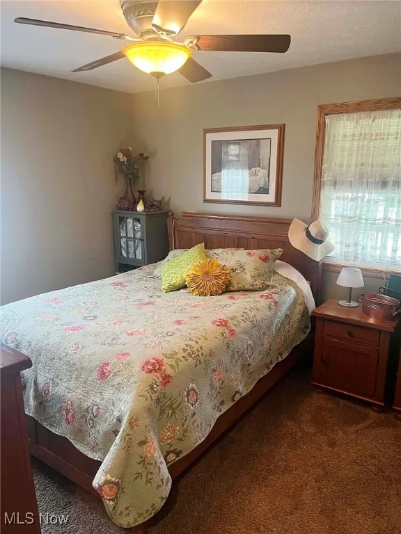 Carpeted bedroom featuring ceiling fan
