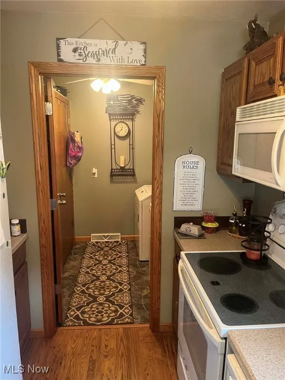 Kitchen featuring white appliances, brown cabinetry, light wood-style floors, and light countertops