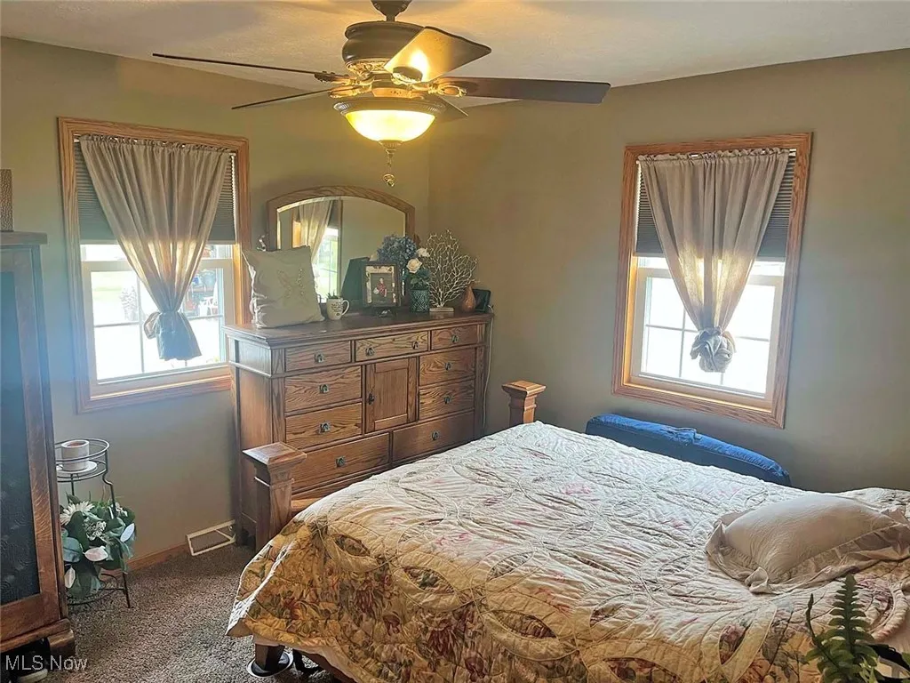 Carpeted bedroom with ceiling fan and baseboards
