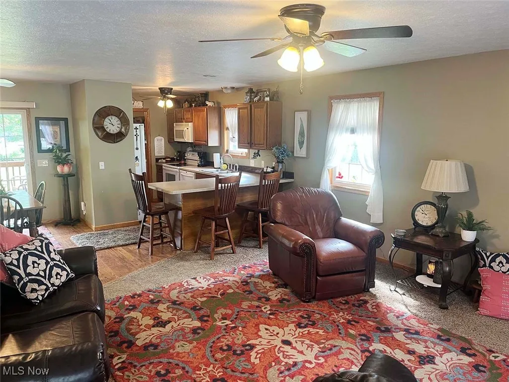Living room featuring a ceiling fan, a textured ceiling, and light wood-style flooring