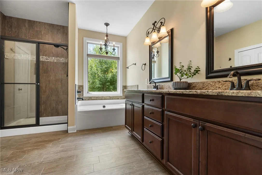 Bathroom featuring double vanity, wood finished floors, a bath, and a shower stall