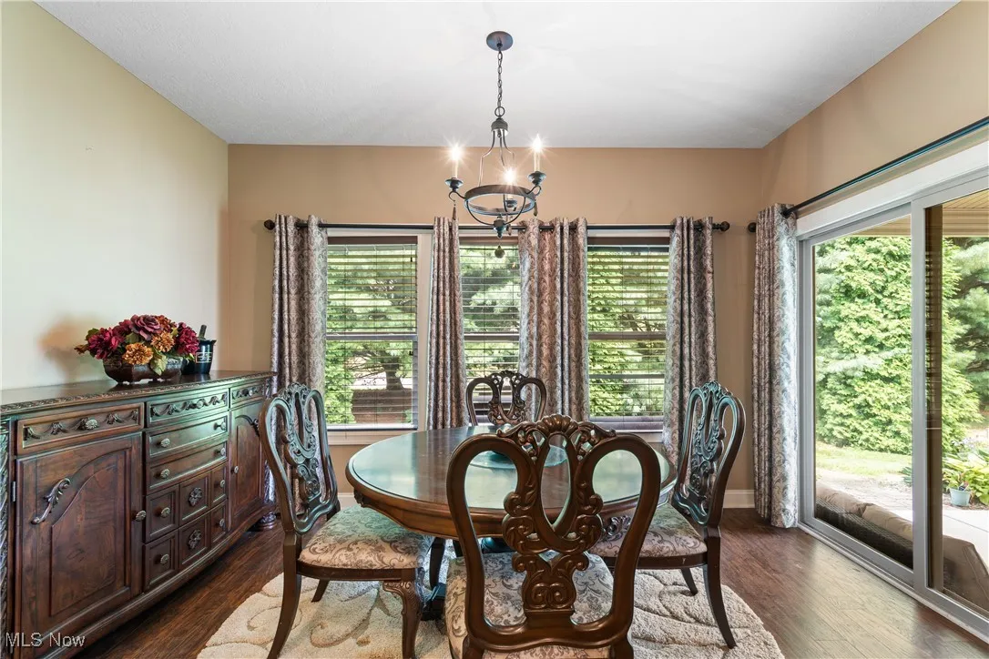 Dining space with a chandelier and dark wood-type flooring