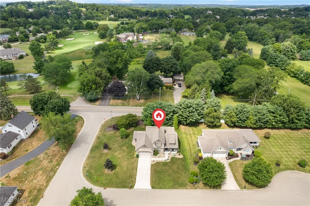 Aerial perspective of suburban area featuring a nearby body of water and a tree filled landscape